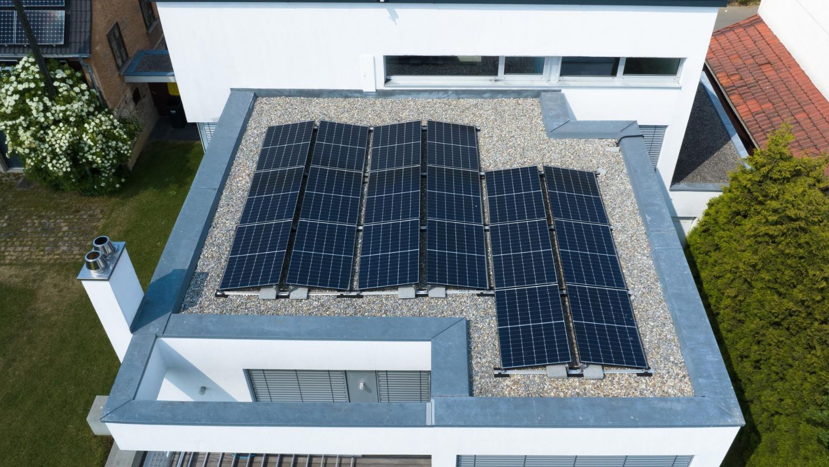 An aerial view of solar panels installed on a flat roof, showcasing the energy efficiency and sustainability advantages of choosing flat roofing in Canada.